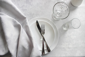  clean dishes on a white table, cutlery in a plate, top view