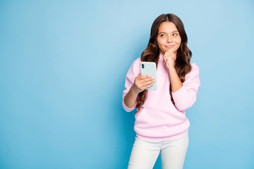 Photo of pretty little lady long wavy hairdo hold telephone think over creative idea for instagram blog post wear casual hoodie pink pullover isolated blue color background
