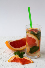 Refreshing summer homemade red grapefruit cocktail with green mint on white background. Detox citrus cocktail. healthy lifestyle.