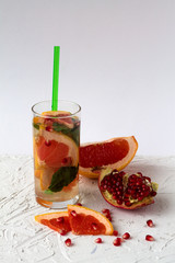 healthy lifestyle. Detox citrus cocktail. Refreshing summer homemade red grapefruit cocktail with ripe pomegranate fruit on white background.