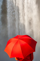 Young Woman WIth Red Umbrella In Front of a Waterfall