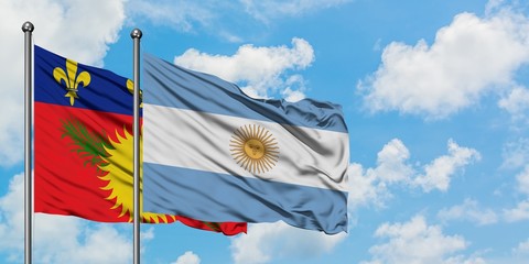 Guadeloupe and Argentina flag waving in the wind against white cloudy blue sky together. Diplomacy...