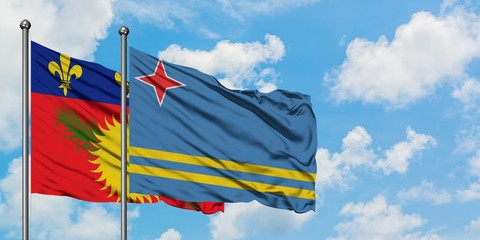 Guadeloupe and Aruba flag waving in the wind against white cloudy blue sky together. Diplomacy concept, international relations.