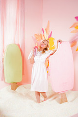 charming happy blonde woman in a soft lace summer dress posing with a huge pink ice cream in the pool with foam soft small balls and engaged in relaxation therapy.