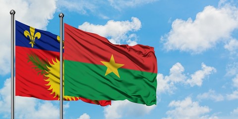 Guadeloupe and Burkina Faso flag waving in the wind against white cloudy blue sky together. Diplomacy concept, international relations.