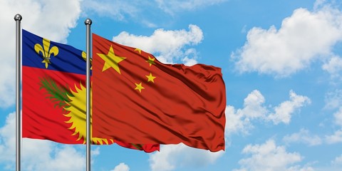 Guadeloupe and China flag waving in the wind against white cloudy blue sky together. Diplomacy concept, international relations.