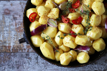 Raw potatoes in a pan with spices before baking. Vegan dinner or lunch.