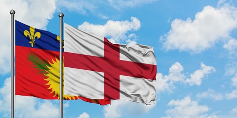 Guadeloupe and England flag waving in the wind against white cloudy blue sky together. Diplomacy concept, international relations.