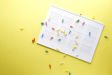 Planning calendar with many pins on a yellow background. Important date. Place for text. Planning concept.