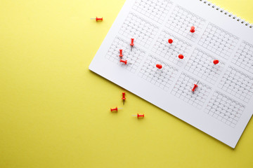 Planning calendar with many red pins on a yellow background. Important date. Place for text. Planning concept.