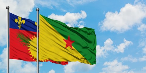Guadeloupe and French Guiana flag waving in the wind against white cloudy blue sky together. Diplomacy concept, international relations.