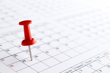 Red pin marking on calendar in planning concept.