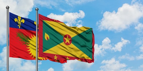 Guadeloupe and Grenada flag waving in the wind against white cloudy blue sky together. Diplomacy concept, international relations.