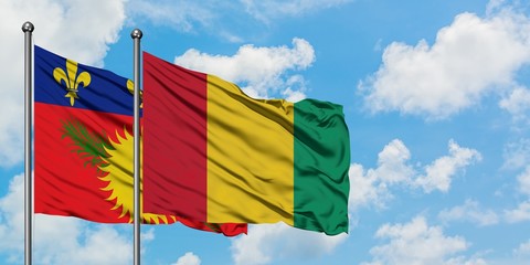 Guadeloupe and Guinea flag waving in the wind against white cloudy blue sky together. Diplomacy concept, international relations.