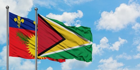 Guadeloupe and Guyana flag waving in the wind against white cloudy blue sky together. Diplomacy concept, international relations.