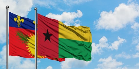 Guadeloupe and Guinea Bissau flag waving in the wind against white cloudy blue sky together. Diplomacy concept, international relations.