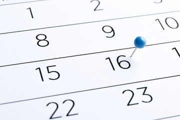 Blue pin on a 16th date on a calendar close-up. Important date. Place for text. Planning concept.