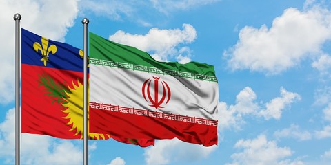 Guadeloupe and Iran flag waving in the wind against white cloudy blue sky together. Diplomacy concept, international relations.