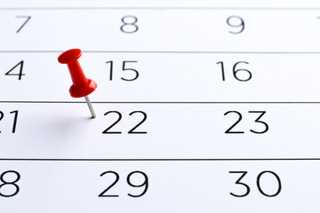 Red pin on the date 22th on the calendar close-up. Important date. Place for text. Planning concept.