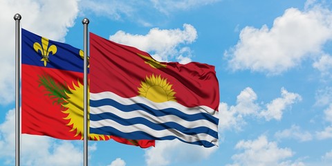 Guadeloupe and Kiribati flag waving in the wind against white cloudy blue sky together. Diplomacy concept, international relations.
