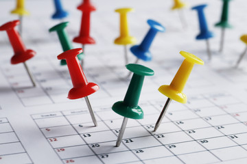 Many multi-colored pins of different dates on a calendar close-up. Important date. Place for text. Planning concept.