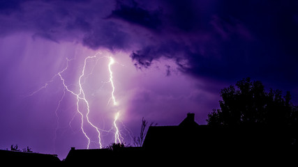 Lightning strikes painting the sky purple in the evening