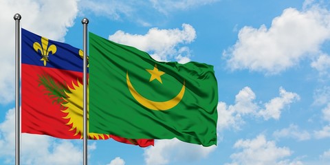 Guadeloupe and Mauritania flag waving in the wind against white cloudy blue sky together. Diplomacy concept, international relations.