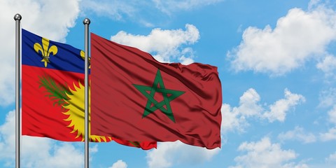 Guadeloupe and Morocco flag waving in the wind against white cloudy blue sky together. Diplomacy concept, international relations.