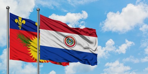 Guadeloupe and Paraguay flag waving in the wind against white cloudy blue sky together. Diplomacy concept, international relations.