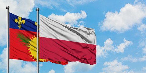 Guadeloupe and Poland flag waving in the wind against white cloudy blue sky together. Diplomacy concept, international relations.