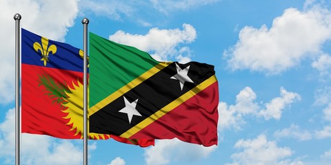Guadeloupe and Saint Kitts And Nevis flag waving in the wind against white cloudy blue sky together. Diplomacy concept, international relations.
