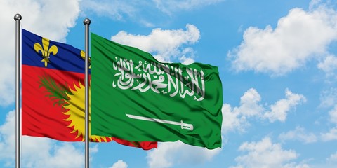 Guadeloupe and Saudi Arabia flag waving in the wind against white cloudy blue sky together. Diplomacy concept, international relations.