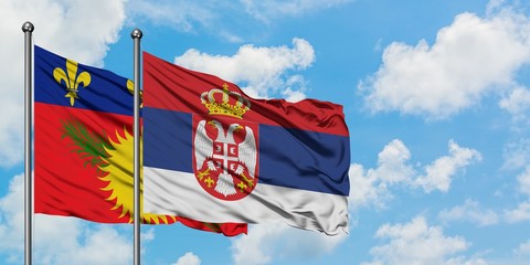 Guadeloupe and Serbia flag waving in the wind against white cloudy blue sky together. Diplomacy concept, international relations.