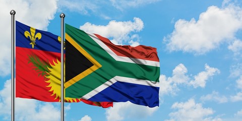 Guadeloupe and South Africa flag waving in the wind against white cloudy blue sky together. Diplomacy concept, international relations.