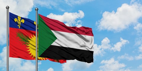 Guadeloupe and Sudan flag waving in the wind against white cloudy blue sky together. Diplomacy concept, international relations.