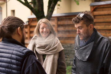 Three friends, two guys and a girl met on the street in the autumn and are having fun talking. One guy smokes a cigarette.