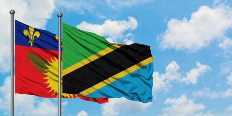 Guadeloupe and Tanzania flag waving in the wind against white cloudy blue sky together. Diplomacy concept, international relations.