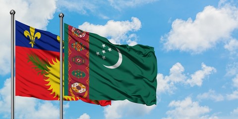 Guadeloupe and Turkmenistan flag waving in the wind against white cloudy blue sky together. Diplomacy concept, international relations.