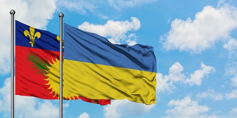 Guadeloupe and Ukraine flag waving in the wind against white cloudy blue sky together. Diplomacy concept, international relations.