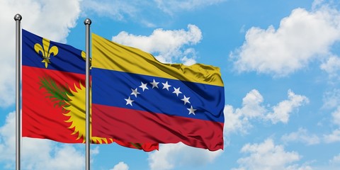 Guadeloupe and Venezuela flag waving in the wind against white cloudy blue sky together. Diplomacy concept, international relations.