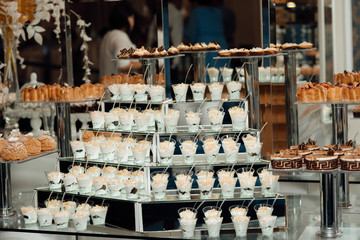 Refrigerated cups of chocolate ice cream. Sweet table on the wedding with delicious desserts. Candy bar. Table with sweet candies. Wedding cake. Dessert table at wedding reception