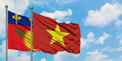 Guadeloupe and Vietnam flag waving in the wind against white cloudy blue sky together. Diplomacy concept, international relations.