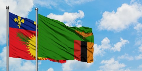 Guadeloupe and Zambia flag waving in the wind against white cloudy blue sky together. Diplomacy concept, international relations.