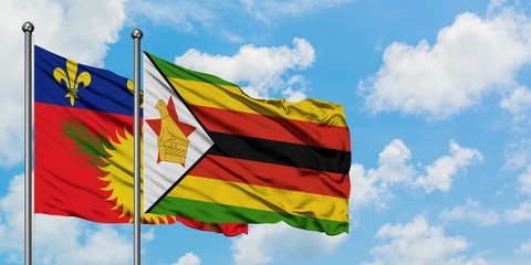 Guadeloupe and Zimbabwe flag waving in the wind against white cloudy blue sky together. Diplomacy concept, international relations.