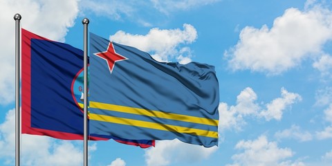 Guam and Aruba flag waving in the wind against white cloudy blue sky together. Diplomacy concept, international relations.