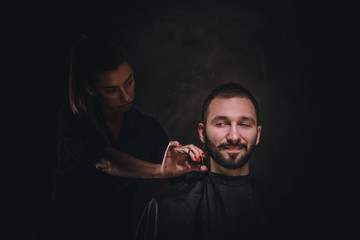Young attractive brunette is visiting a barbershop for a care about his beard.