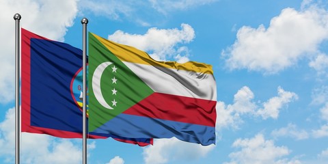 Guam and Comoros flag waving in the wind against white cloudy blue sky together. Diplomacy concept, international relations.