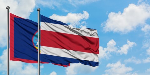 Guam and Costa Rica flag waving in the wind against white cloudy blue sky together. Diplomacy concept, international relations.