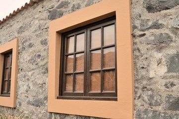 Fototapeta na wymiar Exterior details of a stone building with orange framed windows (Madeira, Portugal, Europe)