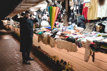 A man chooses and tries on clothes at a flea market.